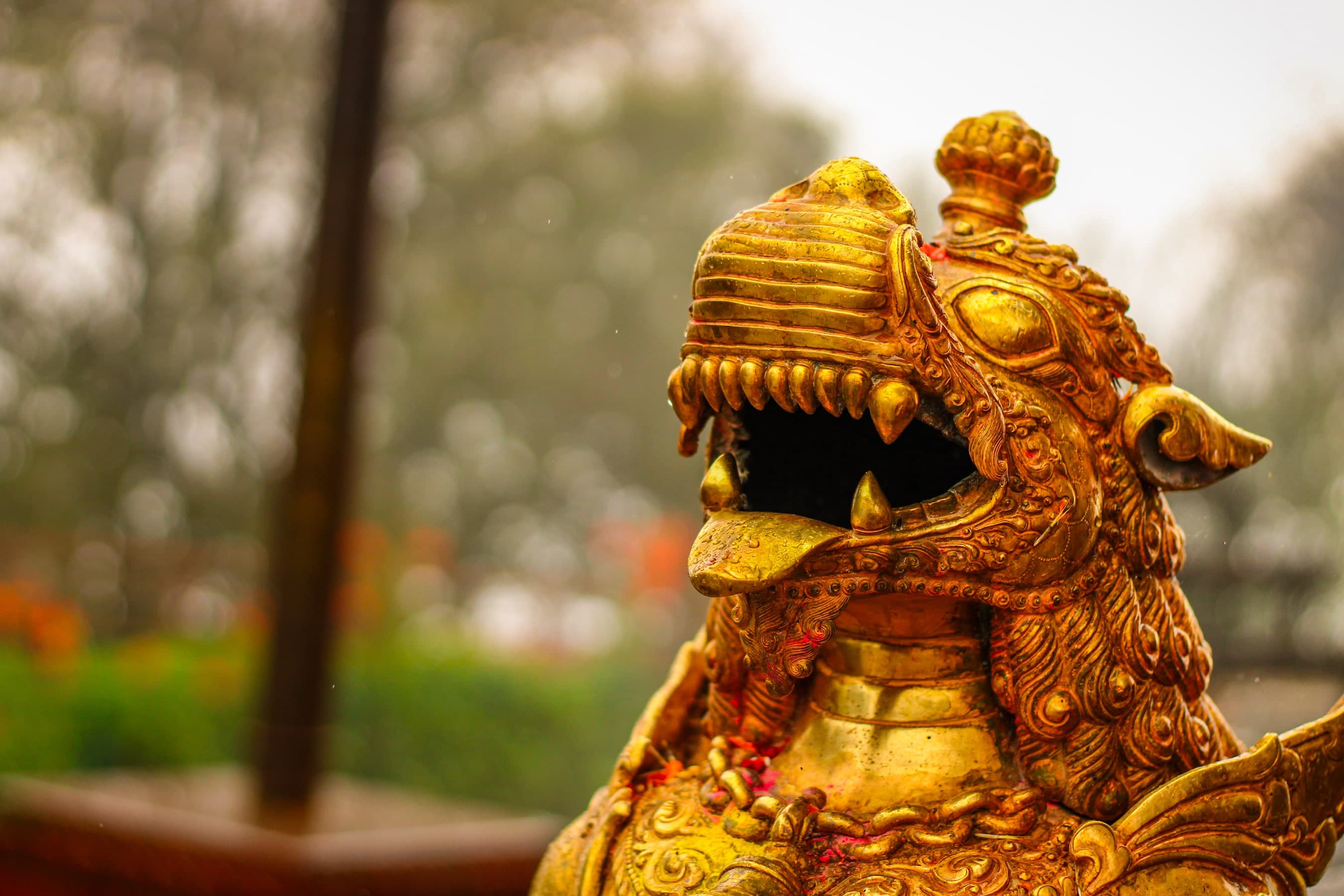 A gold statue of a Lion with a mouth open.