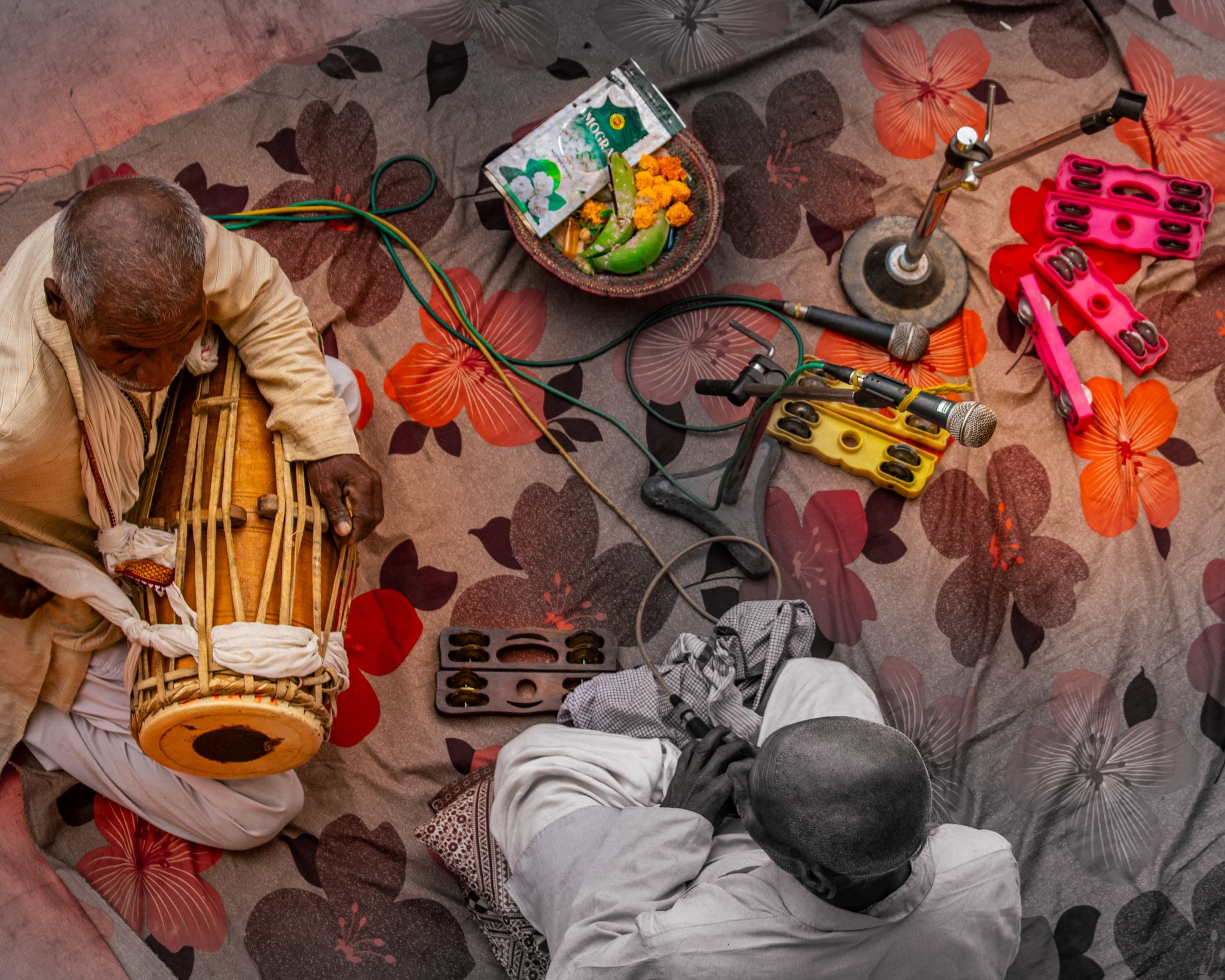 A group of performers sing bhajans with tambourines in hand, offering devotion through music in a spiritual setting.