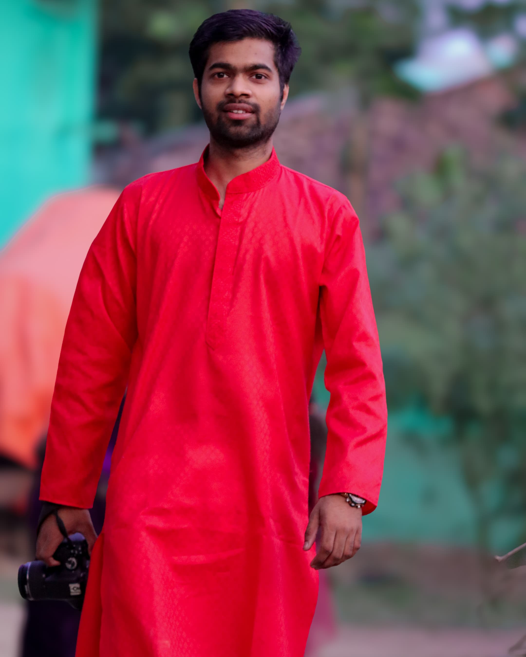 Portrait of Manihs holding a camera outdoors